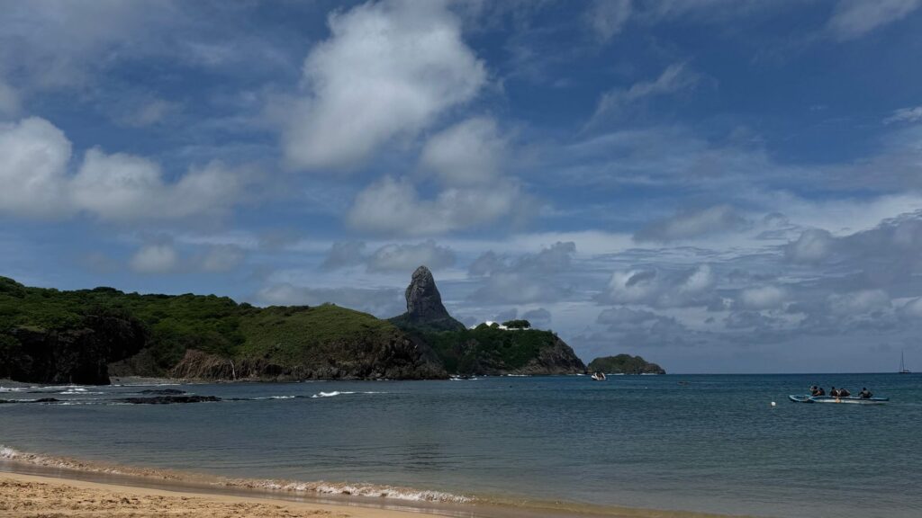 Praia de areia clara com morros verdes ao fundo